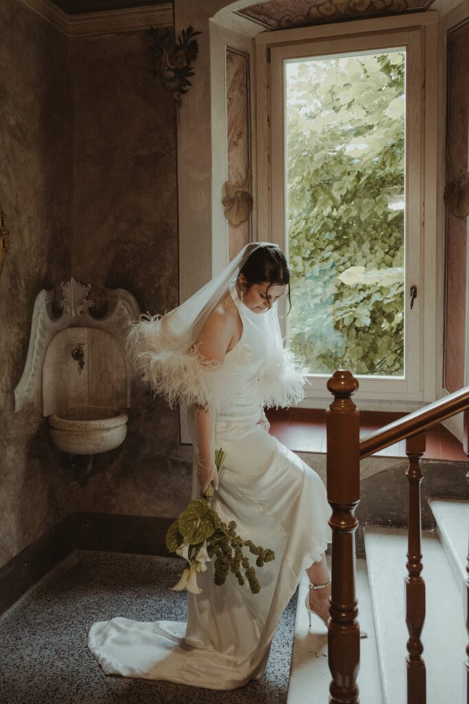 Fließendes Hochzeitskleid aus Satin mit Neckholder und kleiner Schleppe, Schleier und Tüllhandschuhen mit Straußenfedern